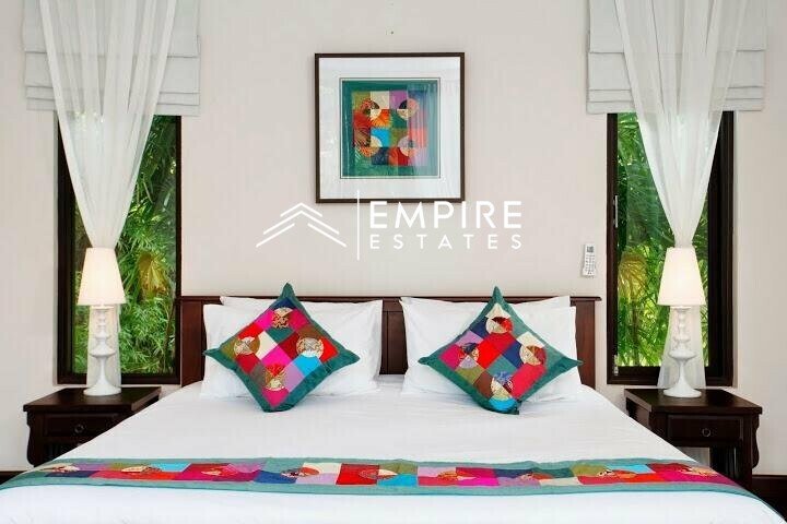 a big bed sitting in a bedroom next to tall windows