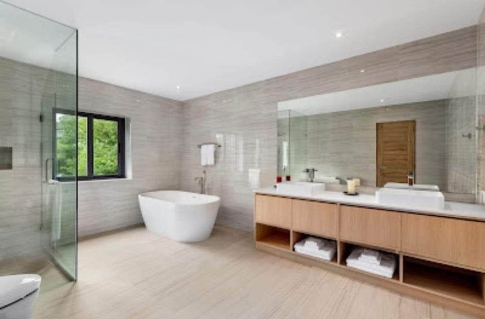 an elegant bathroom with walk in shower, tub, mirror and sink